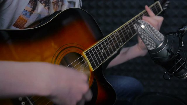 Man playing guitar, recording a song in professional sound studio. HD.