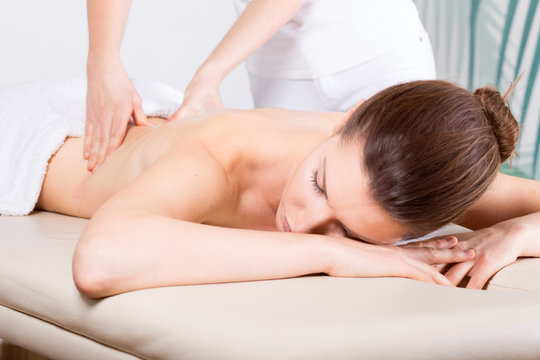 Close-up of young woman receiving back massage/ Close-up image of a young woman who laying on her stomach. She is receiving a back massage.