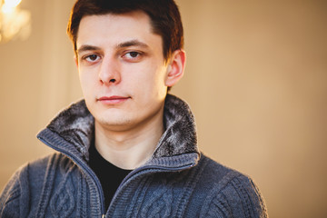 Portrait of young brunette man in a grey pullover ina light room