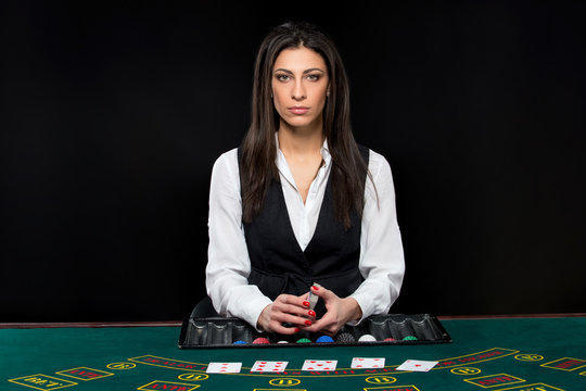 The beautiful girl, dealer, behind a table for poker