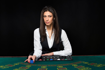 The beautiful girl, dealer, behind a table for poker