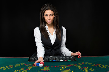 The beautiful girl, dealer, behind a table for poker