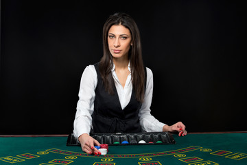 The beautiful girl, dealer, behind a table for poker