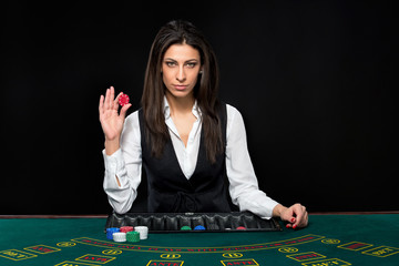 The beautiful girl, dealer, behind a table for poker