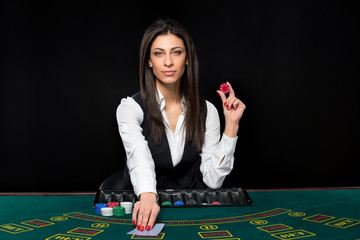 The beautiful girl, dealer, behind a table for poker