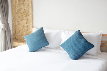 white pillow and blue pillow on bed and with blanket in bedroom