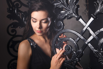 Obraz na płótnie Canvas Portrait of elegant young brunette woman in black long evening dress in interior