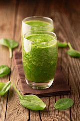 Fresh healthy green spinach smoothie with ingredients on rustic wooden background, selective focus