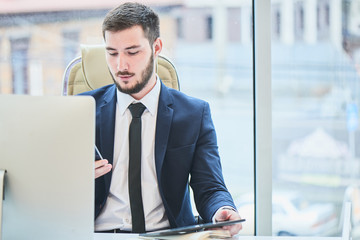 Businessman sitting behind a table holding a tablet and phone
