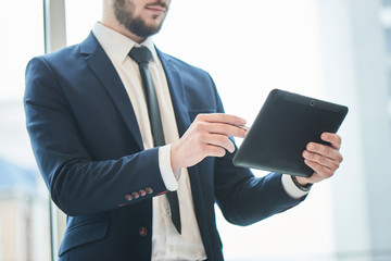 Businessman indicates a ballpoint pen on the tablet which holds in his hand