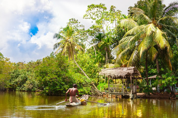 Tropical forest on the river bank .Fisherman floating in a boat.