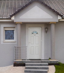 Moderner Eingang eines Einfamilienhauses in grau mit Außentreppe PVC Haustür Vordach mit Säulen...