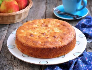 Sponge cake with cream cheese and apple on old wooden background.