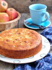 Sponge cake with cream cheese and apple on old wooden background.