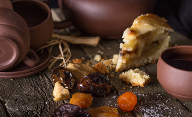 Piece of pie and pottery for tea on an old wooden table