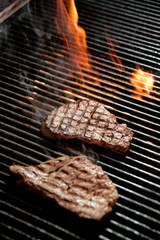 beef steak cooking over flaming grill