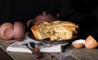Piece of pie and pottery for tea on an old wooden table