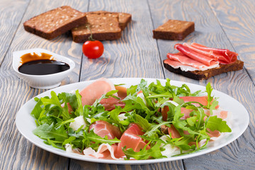 Arugula, prosciutto, mozzarella salad on a white dish