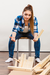 Worried woman assembling wooden furniture. DIY.