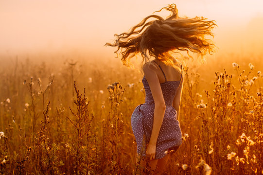 Fototapeta Dancing beautiful girl in fog, field, sun backlight, sunrise, orange colors