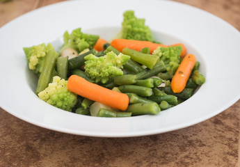Salad with romanesco broccoli, carrot, mushroom, green beans  in white plate