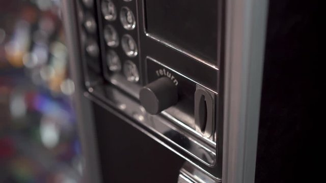 Coins inserted into vending machine to make purchase by child.
