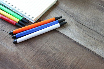 Obraz premium notebook and many pen color on wooden floor.