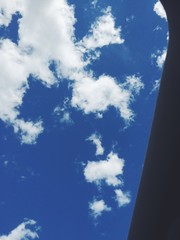 View of blue sky with white puffy clouds through a window