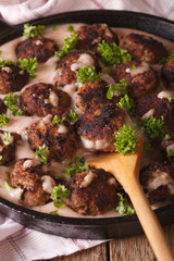 Swedish meatballs in a creamy cowberry sauce closeup on a pan. Vertical
