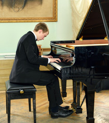 young pianist plays on black grand piano