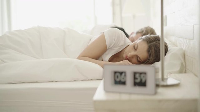 4k footage, alarm clock ringing in the morning, young woman waking up, stretching
