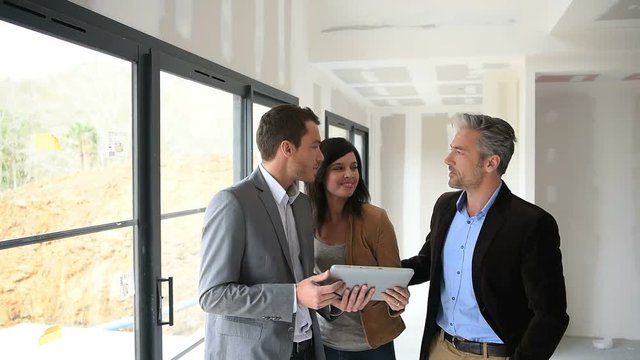 Couple with realtor visiting house under construction