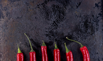 six chilli peppers on rusty metal background