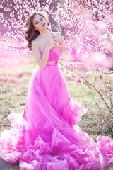 Obraz na płótnie Canvas Adorable girl in blooming peach garden on sunny spring day