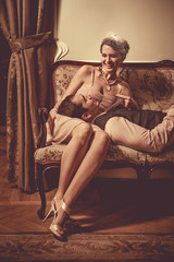 Young flirting couple is laying on the sofa. Vintage post proces