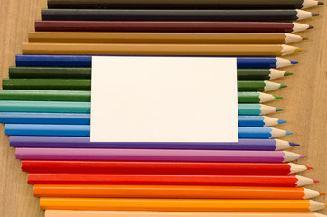 Fototapeta premium Blank white paper and colored pencil on wooden background