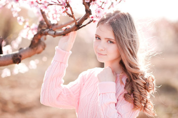 Smiling teen girl 14-16 year old wearing cozy pink sweater outdoors. Looking at camera. Holding...