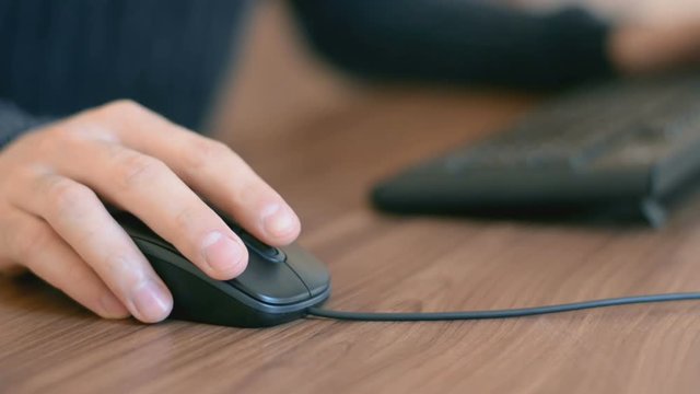 Hand of a man working at computer clicking on mouse