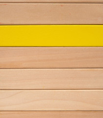 wooden toy blocks with one piece in yellow others in natural color as background