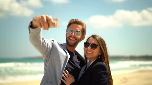4k footage of happy young rich couple making selfies on beachfront with smartphone
