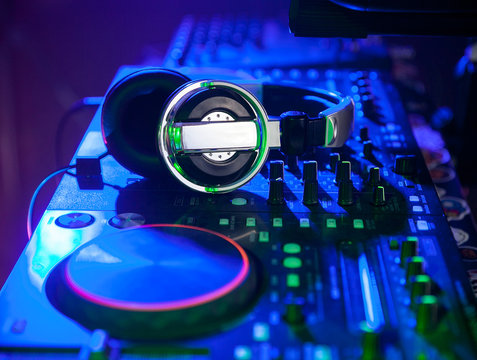 dj headpones on mixing controller in blue light. closeup