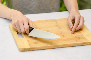 cooking theme: a man holding a knife next to a wooden cutting board on a background of green grass in summer