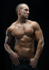 Fototapeta na wymiar Bodybuilder and strip theme: beautiful with pumped muscles naked man posing in the studio on a dark background