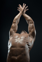 Bodybuilder and strip theme: beautiful with pumped muscles naked man posing in the studio on a dark background