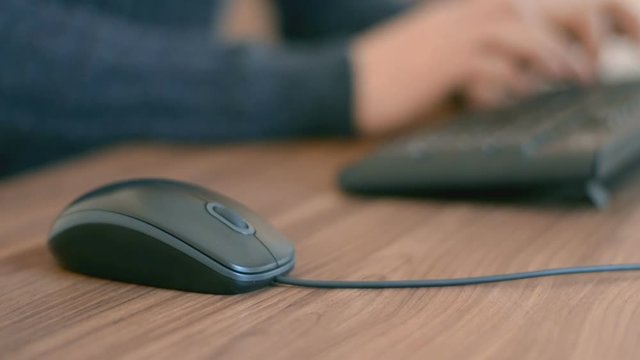 Hand of a man working at computer clicking on mouse typing text on keyboard