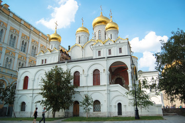 Золотые купола и кресты Собора пресвятой богородицы на территории Московского Кремля на фоне голубого неба. 

