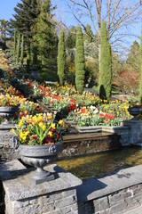 Gartenanlage mit Wasserlauf und eleganten Pflanzgefäßen im Frühling, Parkanlage