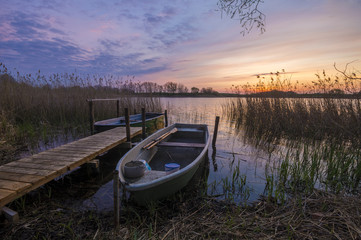 łódki zacumowane do drewnianego pomostu nad jeziorem