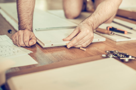 young man collects furniture, tools and parts laid out on the floor