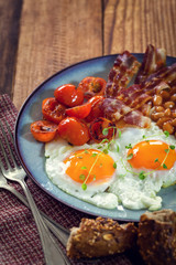 Breakfast with fried eggs, bacon, beans and cherry tomatoes  